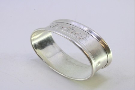 Argola de guardanapo em prata de forma oval com frisos na envolvência e dizeres "BÉBÉ".